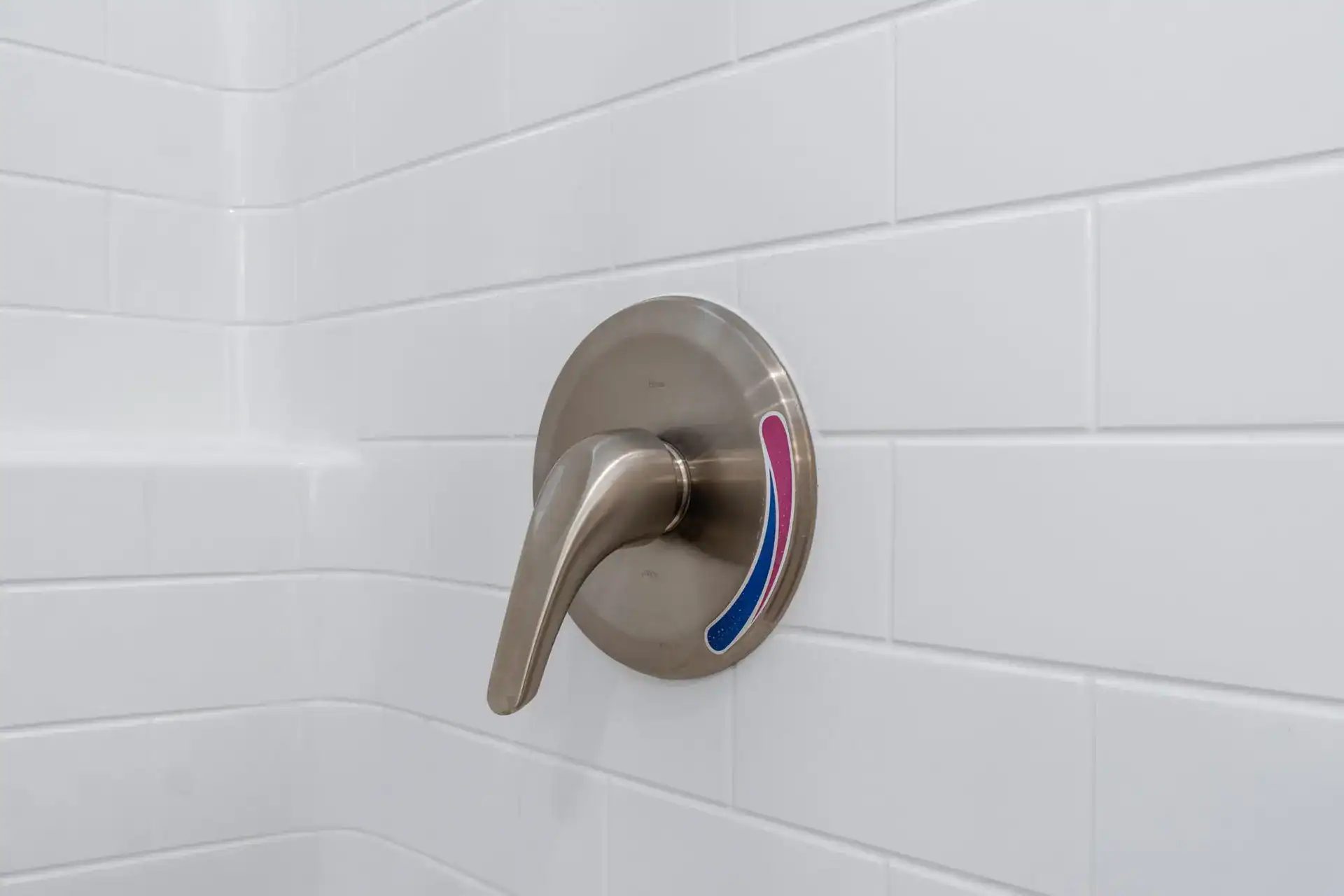 Modern shower faucet with temperature control in a tiled bathroom.