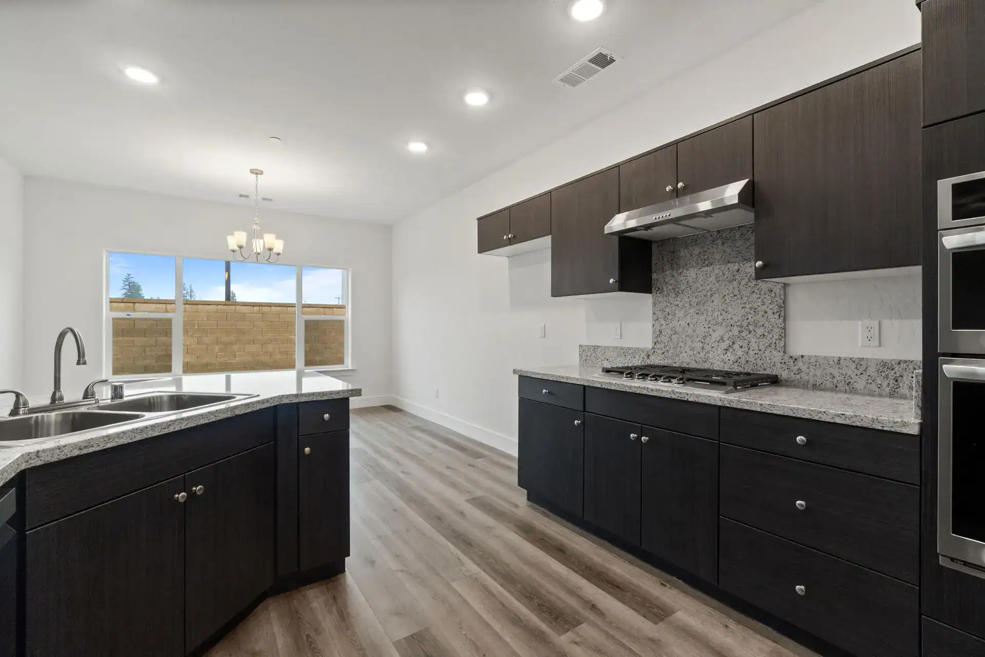 Modern kitchen with dark cabinets, granite countertops, and stainless steel appliances.