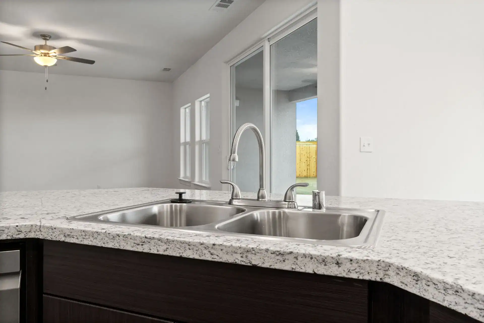 Modern kitchen sink with granite countertop and bright natural light.