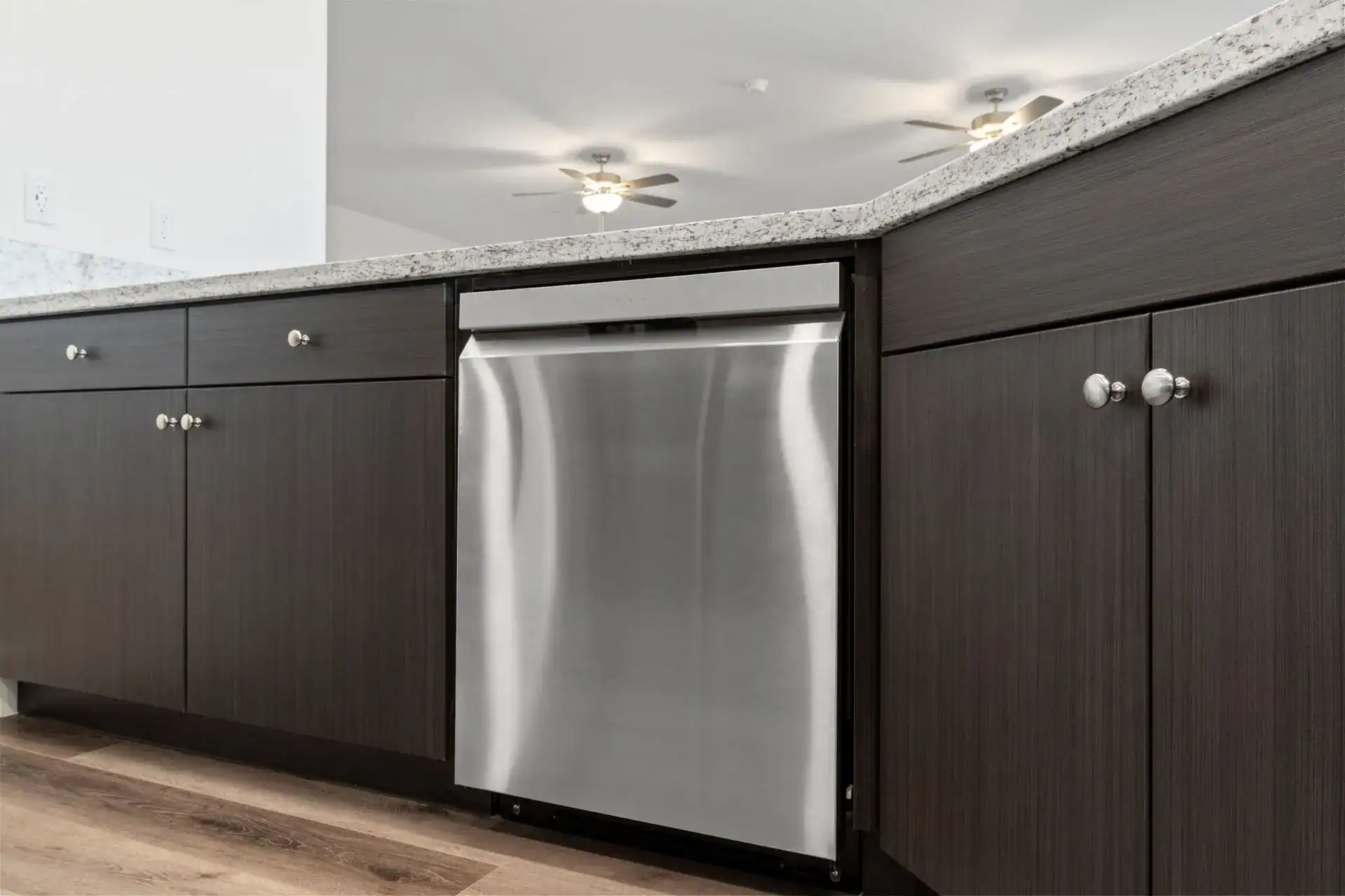 Kitchen cabinetry with stainless steel dishwasher and granite countertop.
