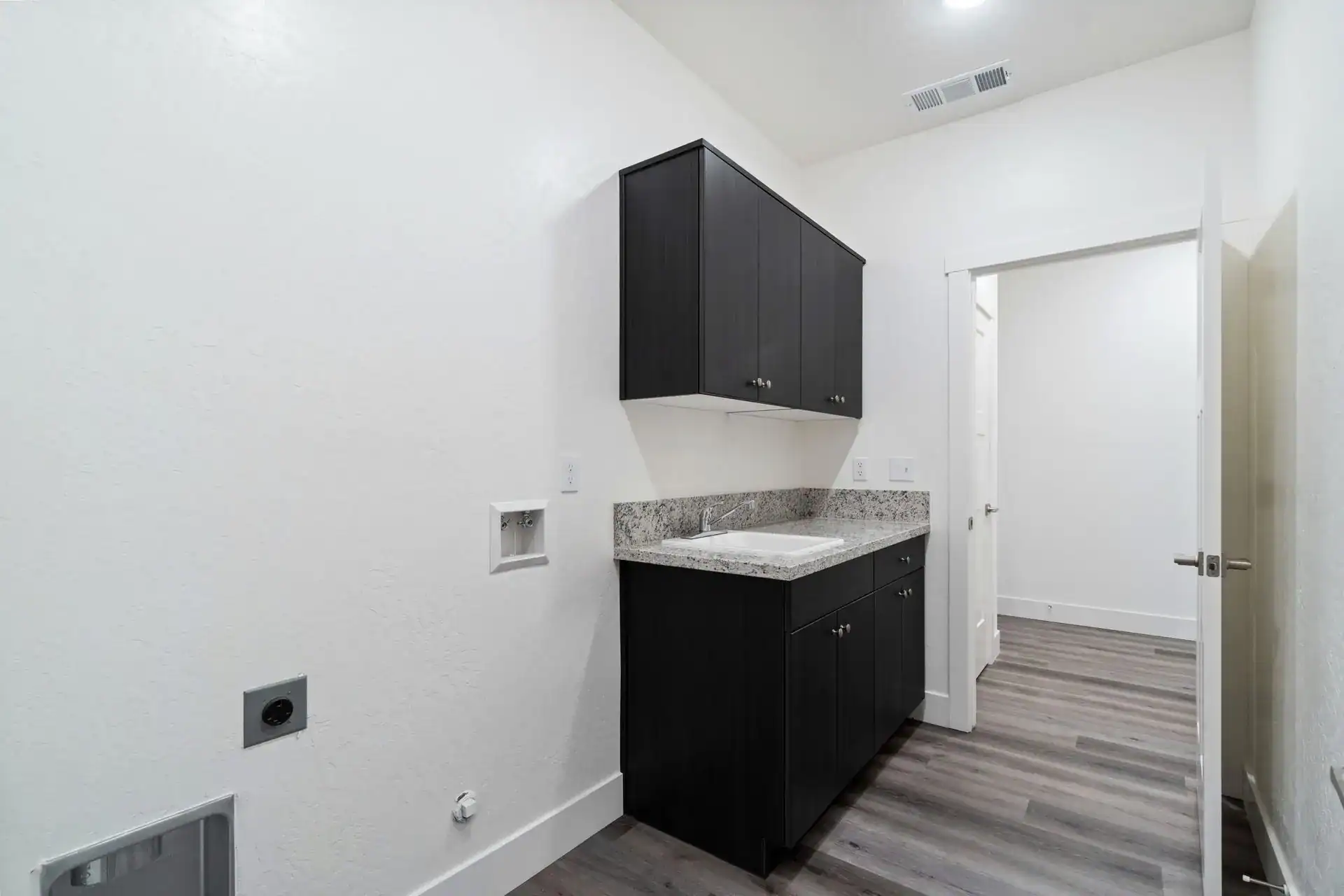 Laundry room with black cabinets and granite countertop in a modern home.