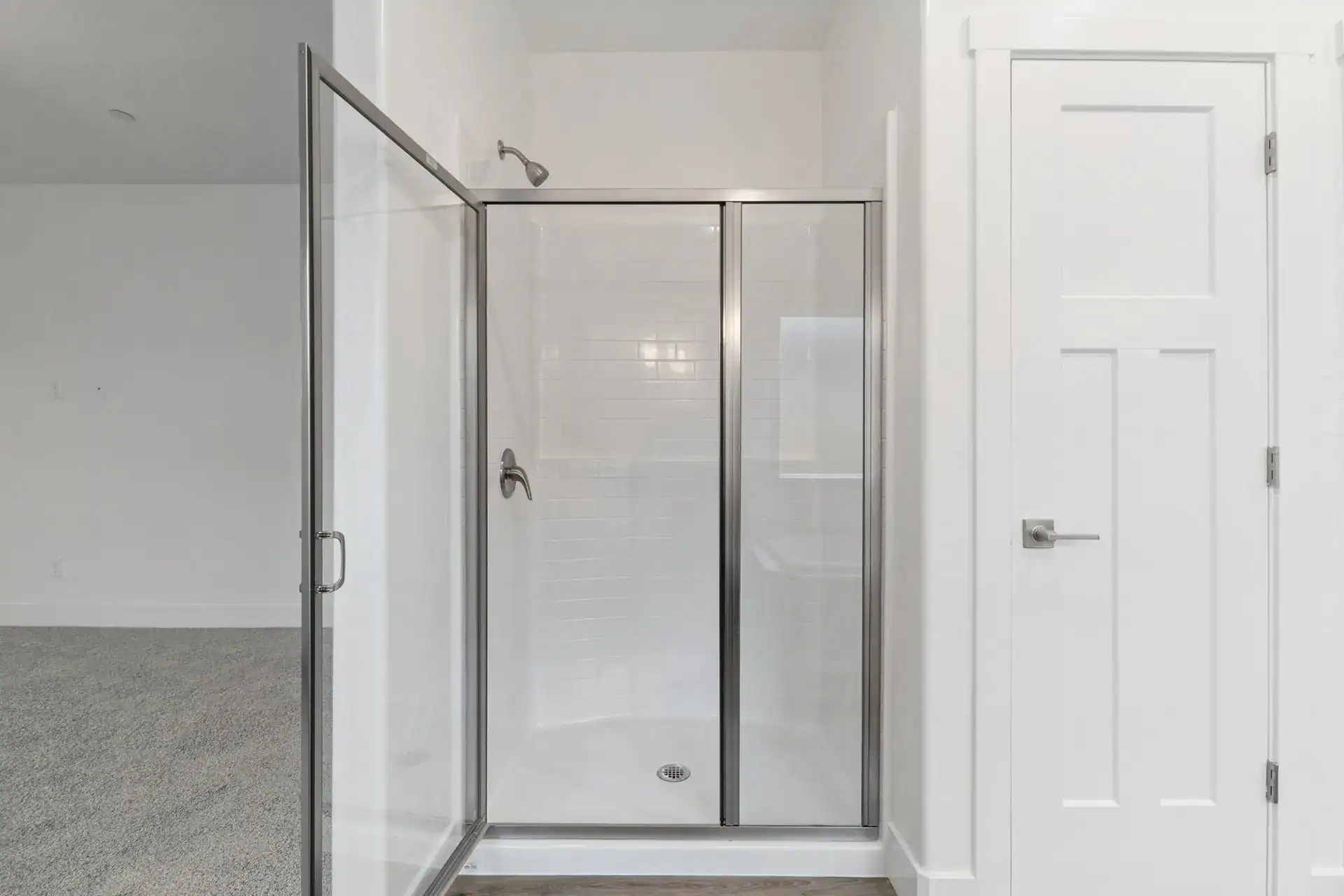 Glass shower enclosure with clear panels and metal frame.