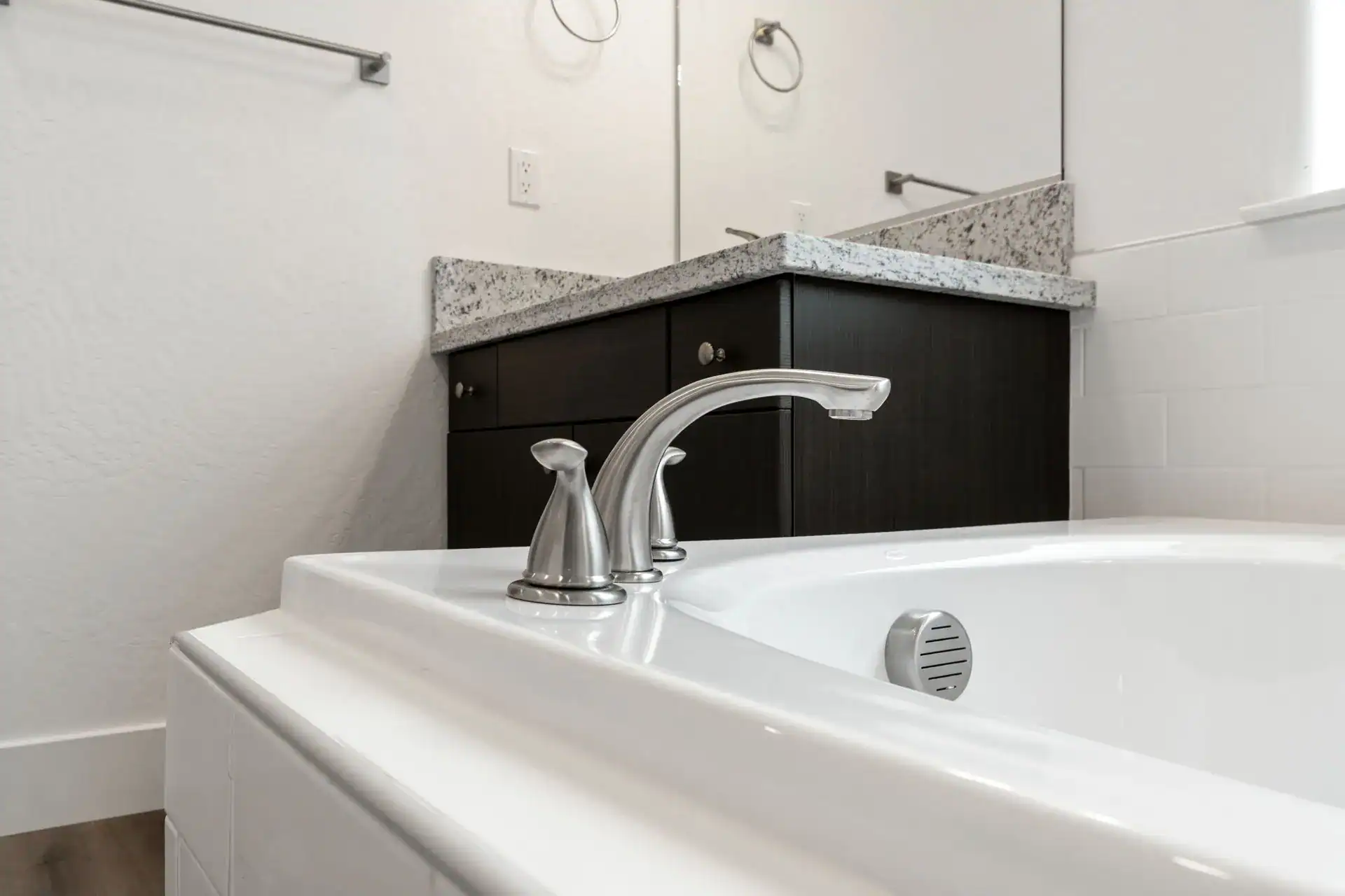 Modern bathroom with granite countertop and white bathtub.