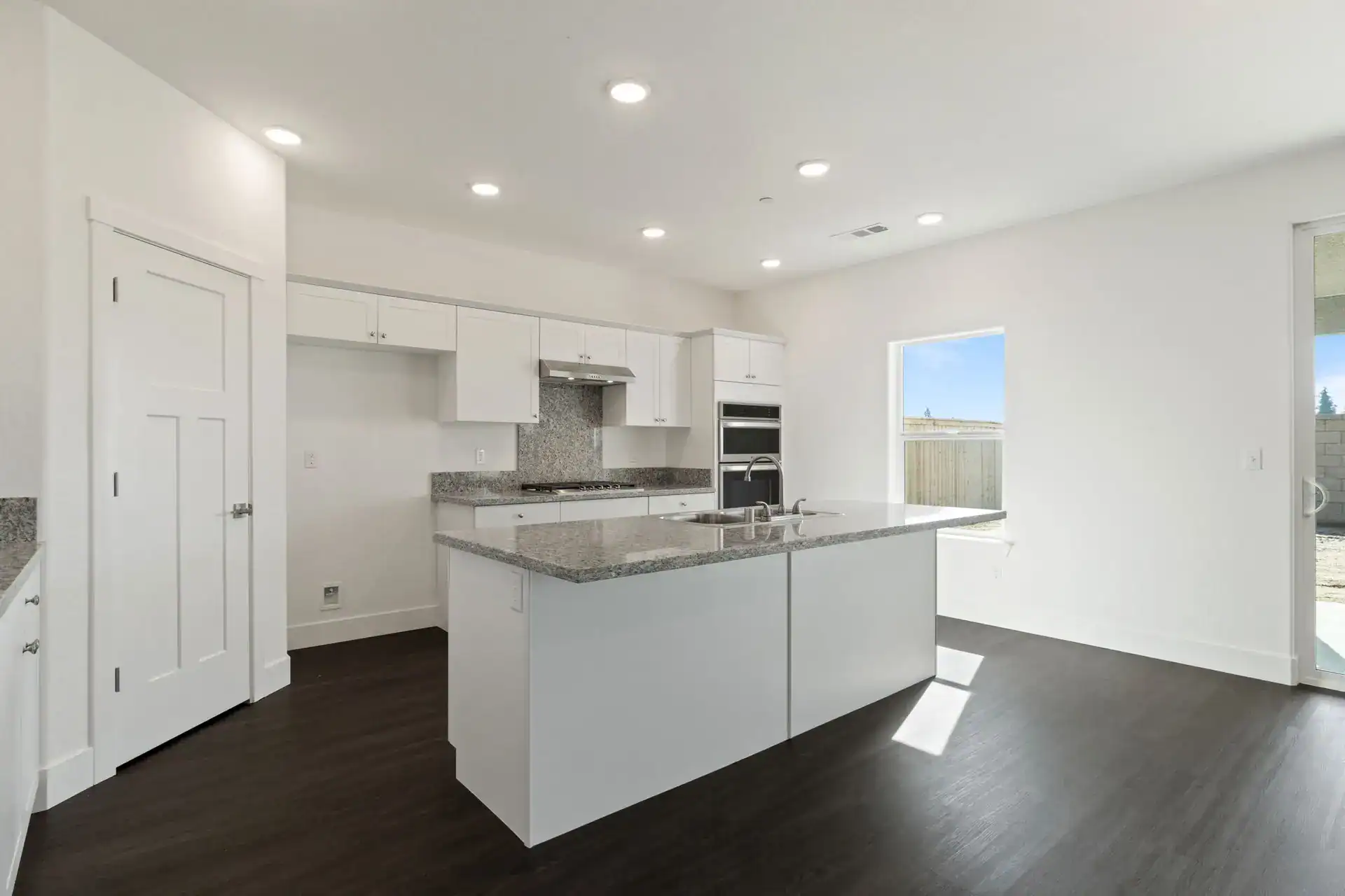 Modern white kitchen with island and stainless steel appliances.