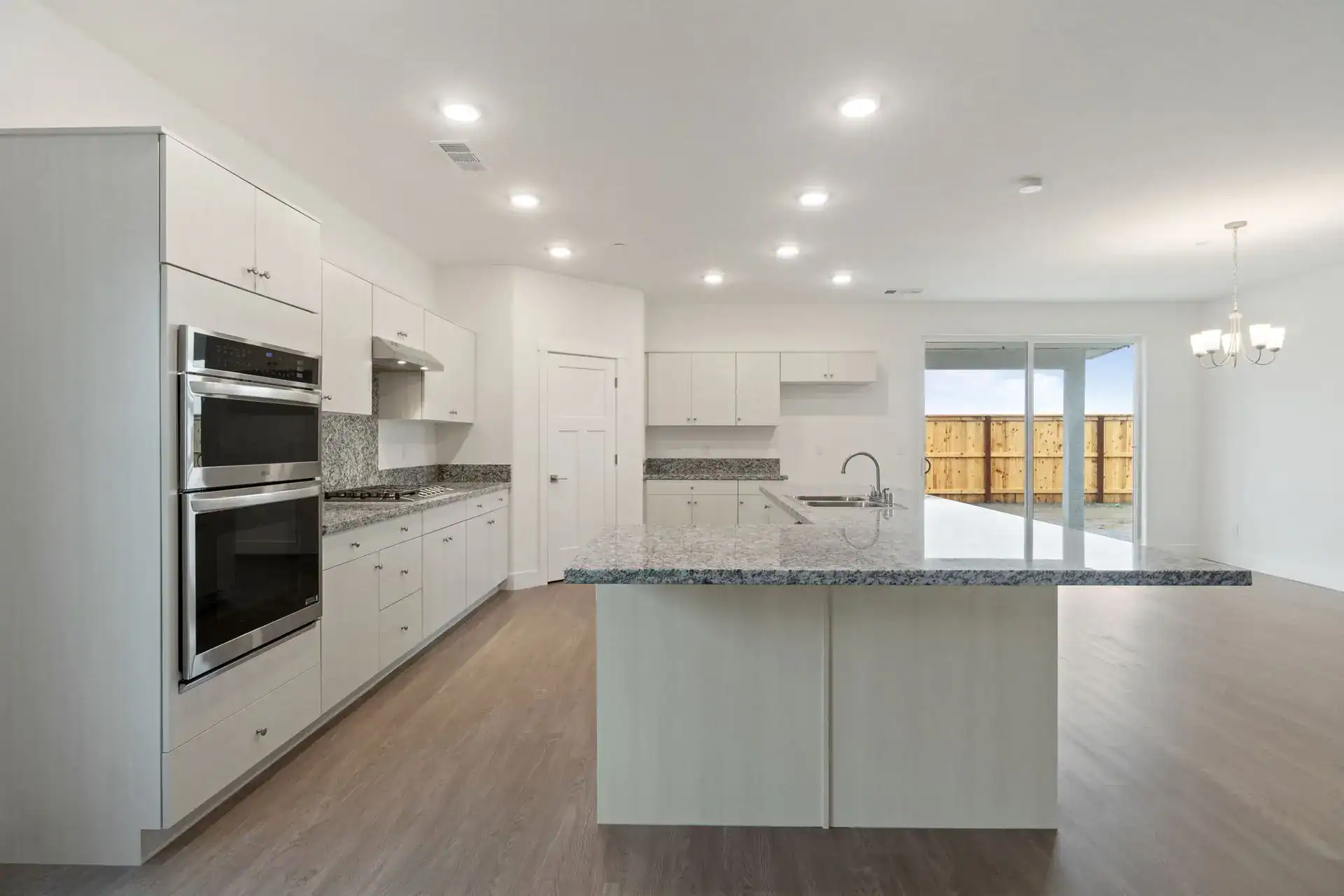 Bright modern kitchen with white cabinets, island, and stainless steel appliances.
