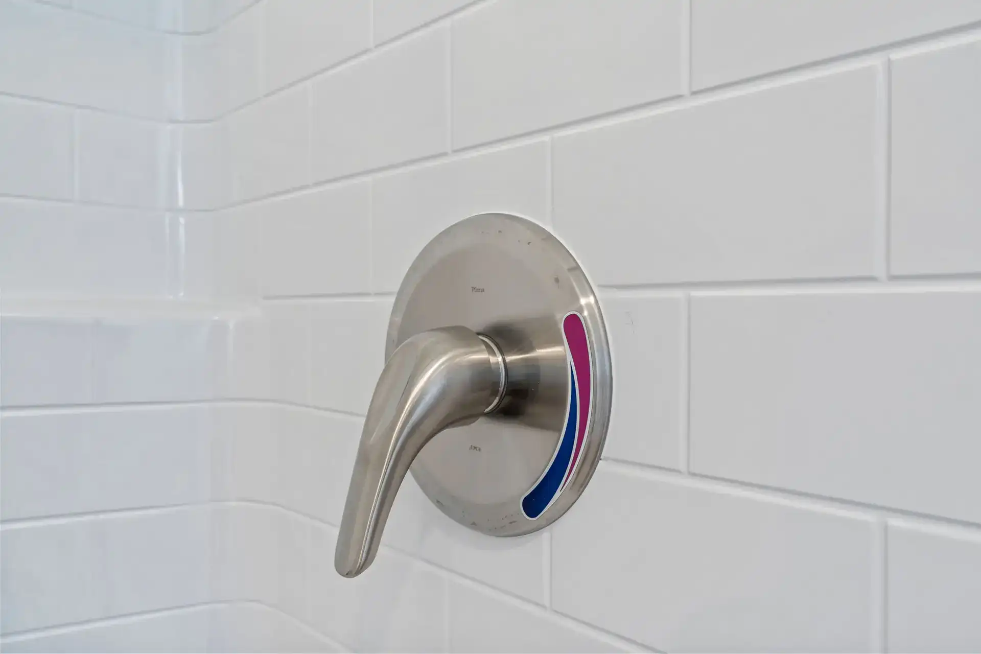 Shower faucet with temperature control in a tiled bathroom.